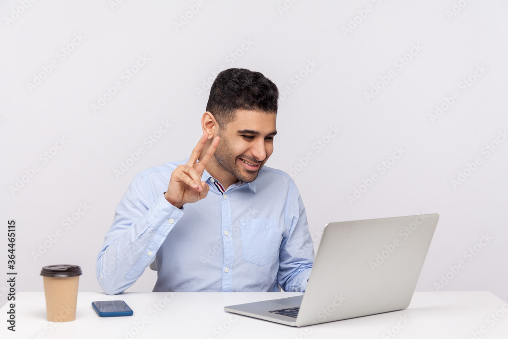 This is win! Businessman sitting office workplace, showing victory gesture to laptop screen, talking online video call, discussing successful work project. studio shot isolated on white background This is win! Businessman sitting office workplace, showing victory gesture to laptop screen, talking online video call, discussing successful work project. studio shot isolated on white background