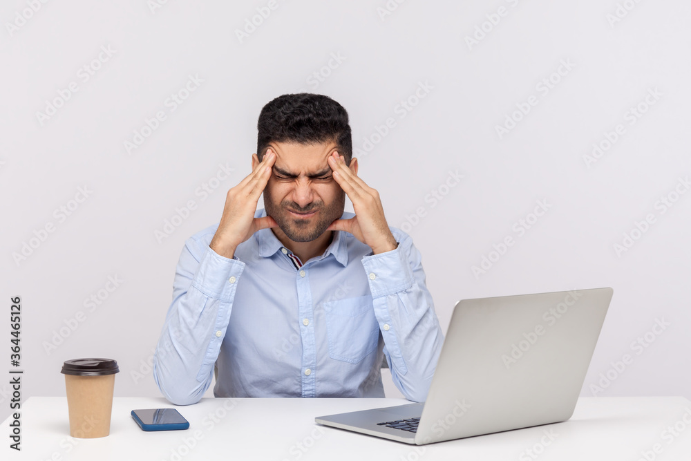 Unhealthy tired businessman sitting office workplace, clasping painful head, suffering severe migraine of overwork and stressful job, worried about troubles. studio shot isolated on white background Unhealthy tired businessman sitting office workplace, clasping painful head, suffering severe migraine of overwork and stressful job, worried about troubles. studio shot isolated on white background