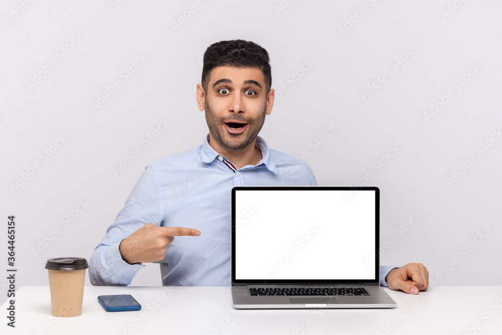 Wow, look at advertisement! Amazed man employee sitting in office workplace, pointing laptop blank display and looking surprised shocked expression, mock up for website promotion. studio shot isolated Wow, look at advertisement! Amazed man employee sitting in office workplace, pointing laptop blank display and looking surprised shocked expression, mock up for website promotion. studio shot isolated