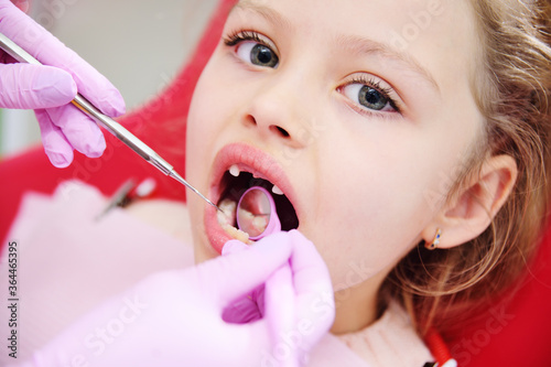 the child is a sweet little girl without front milk teeth in the dental chair. The dentist examines the teeth of the child's patient. Pediatric dentistry