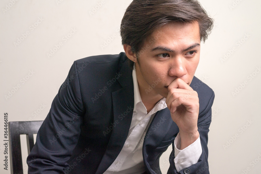 Face of stressed young Filipino businessman in suit thinking Face of stressed young Filipino businessman in suit thinking