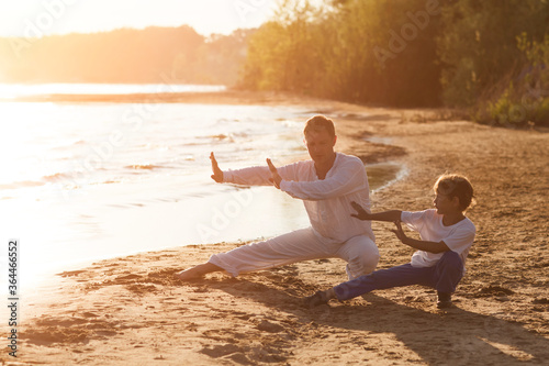 Family dad and son preschool child practice Tai Chi Chuan in the summer on the beach. Chinese management skill Qi's energy. solo outdoor activities. Social Distancing. family exercising together 