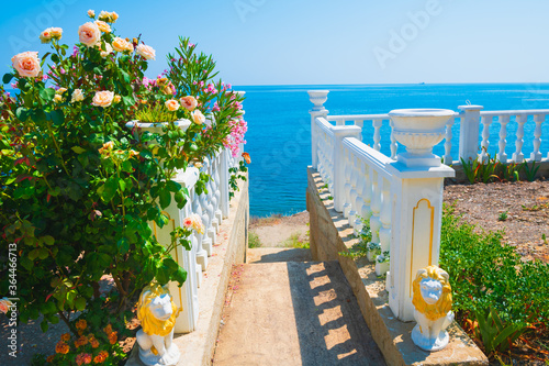 Beautiful garden with roses on the terrace with sea view. Stairs to the sea. Summer landscape, travel destination concept. Crimea, Russia