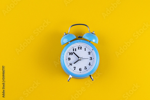 Blue vintage alarm clock on yellow color background. Alarm clock with place for text. Time management concept, business planning