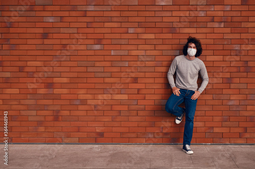 Relaxed man in mask leaning on wall