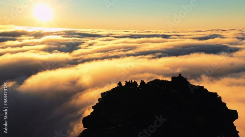 Aerial, drone view orbiting around hikers, on the summit of the on Mount Hassell Mountain, above clouds, during sundown, in West Australia photo