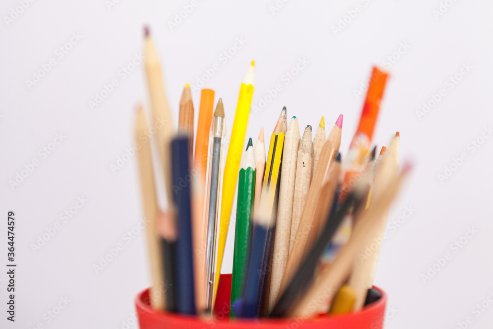 Fototapeta premium Un puñado de lápices con diferentes tamaños y colores dentro de un vaso de plástico.