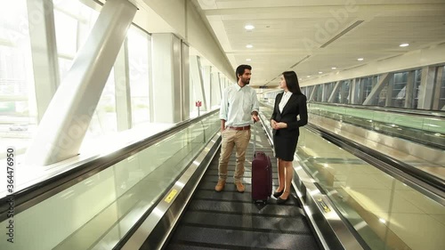 Two business travelers, man and woman on the travellator in the airport