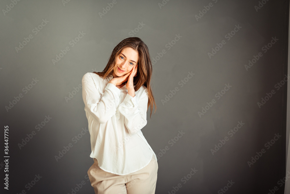 Young girl in a white shirt, hands up, on a gray background. Honest and emotional on the banner, billboard, billboard. No retouch. Without make-up. Young girl in a white shirt, hands up, on a gray background. Honest and emotional on the banner, billboard, billboard. No retouch. Without make-up.