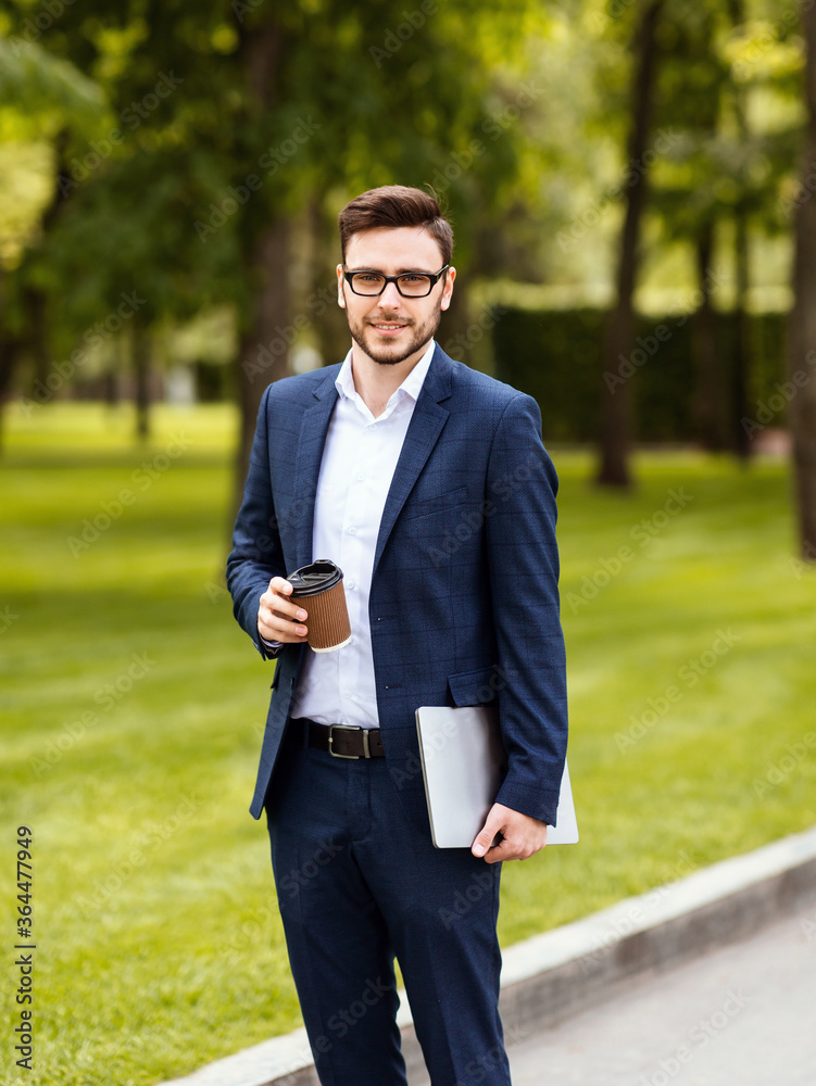 Portrait of handsome young business leader with tablet computer and coffee to go at summer park Portrait of handsome young business leader with tablet computer and coffee to go at summer park