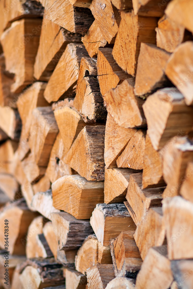 Firewood in logs, large and small chopped branches. Chipped firewood is in storage. Finished firewood for the bath and fireplace. Background of firewood. Natural fuel for the fireplace Firewood in logs, large and small chopped branches. Chipped firewood is in storage. Finished firewood for the bath and fireplace. Background of firewood. Natural fuel for the fireplace