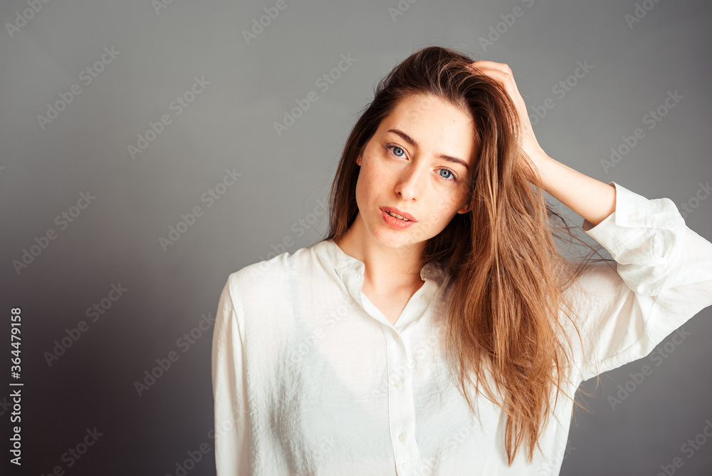 Smiling girl with a satisfied face hands near the face on a gray background, close-up. Nude makeup, without retouching. Smiling girl with a satisfied face hands near the face on a gray background, close-up. Nude makeup, without retouching.