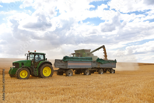 combine harvester and tractor in the cereal field during the summer harvest