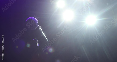 Musical instrument concept, vocal equipment. Professional concert microphone on stage for record or speak to audience in dark in the spotlight. Camera in motion.