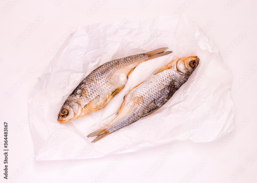 Two dried fishes in white paper on the white background Two dried fishes in white paper on the white background