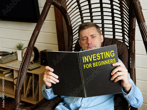 Fotografie Man reads investing for beginners book at home.