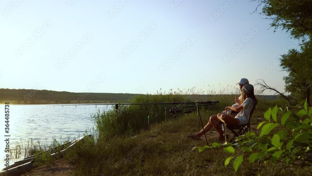 Parent and child spending time together fishing on river bank Parent and child spending time together fishing on river bank