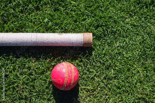 Cricket ball and bat handle isolated on a green background photo