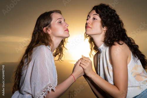 Beautiful young girls posing together at sunset in a sunflower field