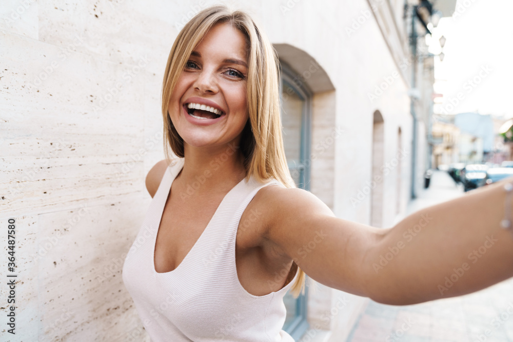 Image of cheerful caucasian woman smiling and taking selfie photo