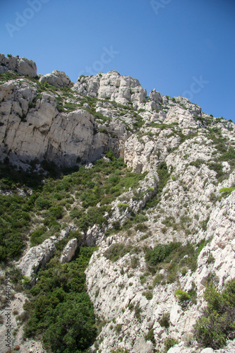 Natural Landscape of mountainside with small rocks and green bushes under blue sky in the Calanques de Marseille in France