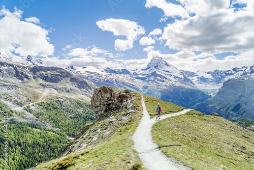 Hiker on a trail choosing one path over another in a beautiful mountain scenery, as a metaphorical decision