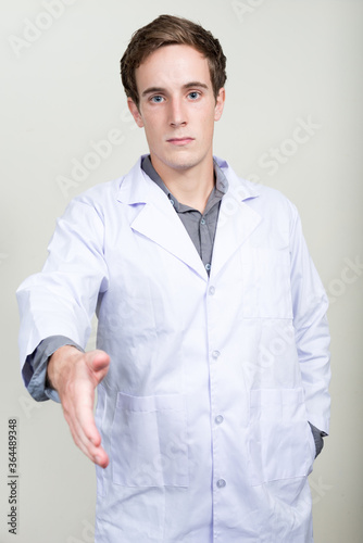 Portrait of young handsome man doctor giving handshake © Ranta Images