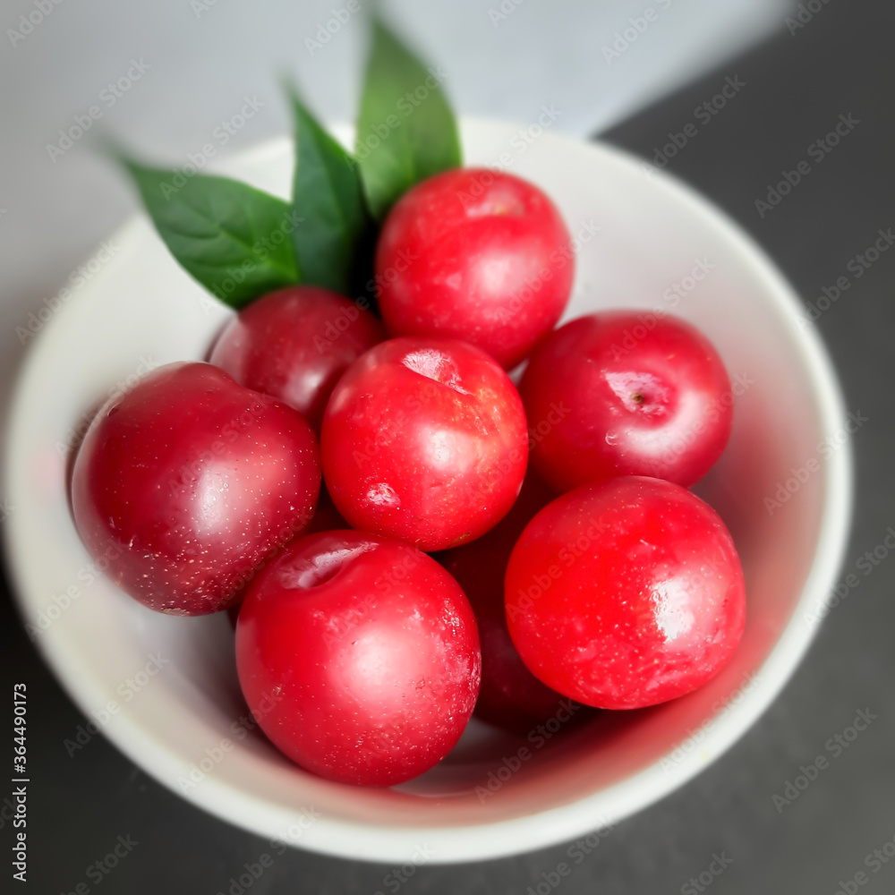 Colorful Red plums kept in bowl with leaves placed in white and black background and reduce the risk of cancer heart disease and diabetes Colorful Red plums kept in bowl with leaves placed in white and black background and reduce the risk of cancer heart disease and diabetes