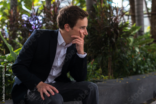 Profile view of young handsome businessman thinking at the park