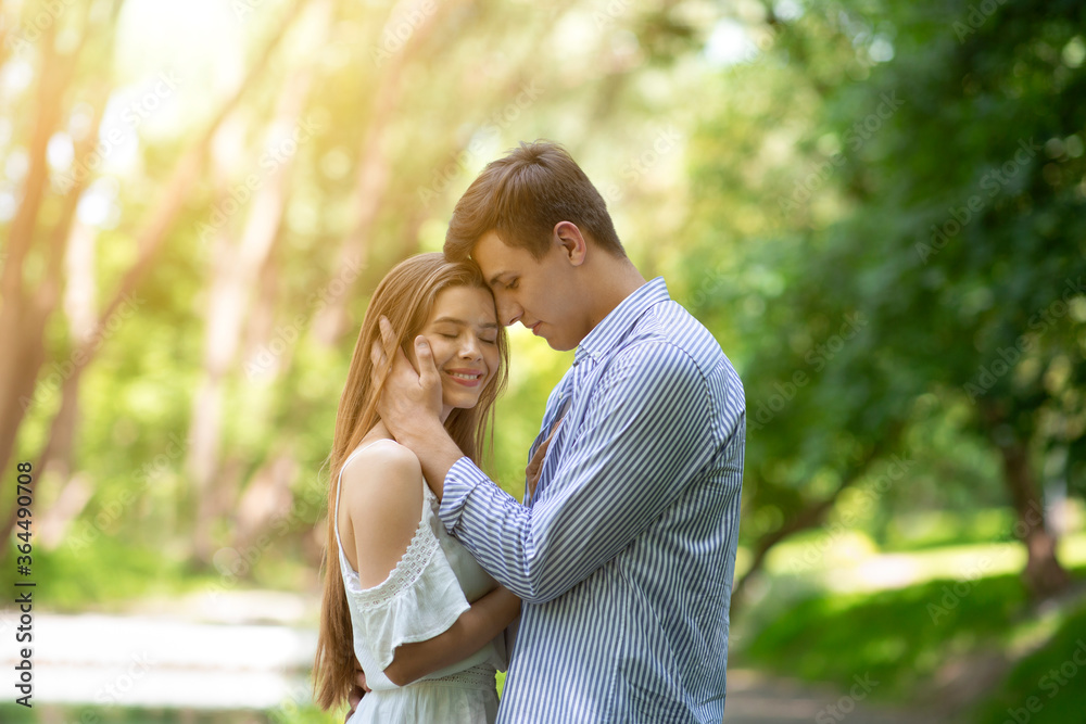 Affectionate young man caressing his girlfriend's face and hugging her outdoors Affectionate young man caressing his girlfriend's face and hugging her outdoors