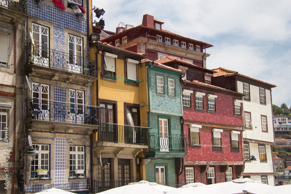 Facades of typical and old residential buildings with very colorful tiles lined with different heights in Ribeira Porto Portugal in front of the river