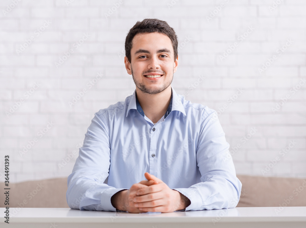 Online meeting and work from home. Smiling friendly guy in shirt with hands on table Online meeting and work from home. Smiling friendly guy in shirt with hands on table