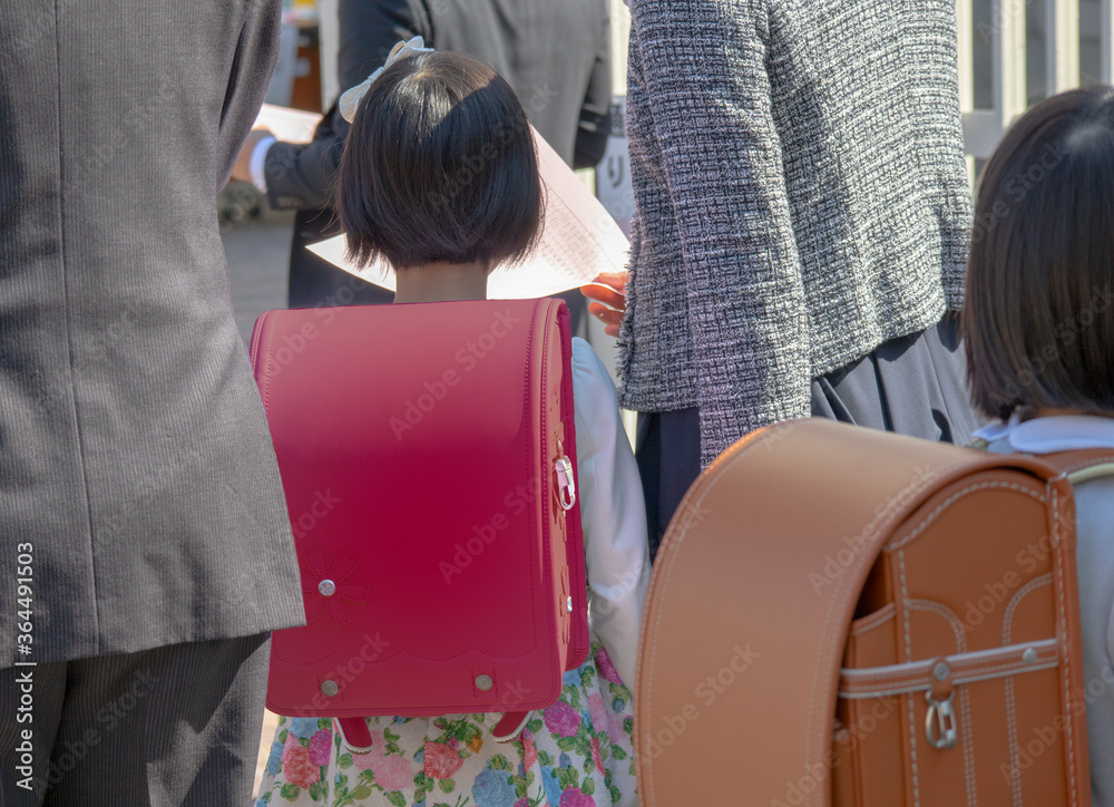 入学式に向かう赤いランドセルをしょった新一年生の女の子とその両親 入学式に向かう赤いランドセルをしょった新一年生の女の子とその両親