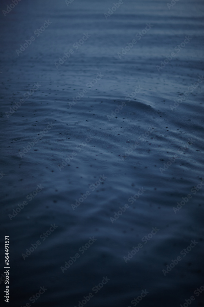 background as raindrops falling on water in a lake
