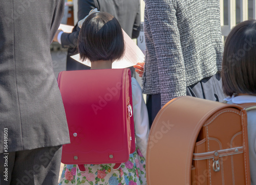 入学式に向かう赤いランドセルをしょった新一年生の女の子とその両親	 photo