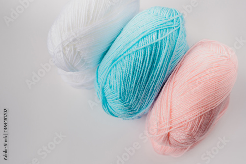 acrylic soft pastel pink, azure and white colored wool yarn thread skeins row on white background, top view, horizontal stock photo image mockup with copy space for text