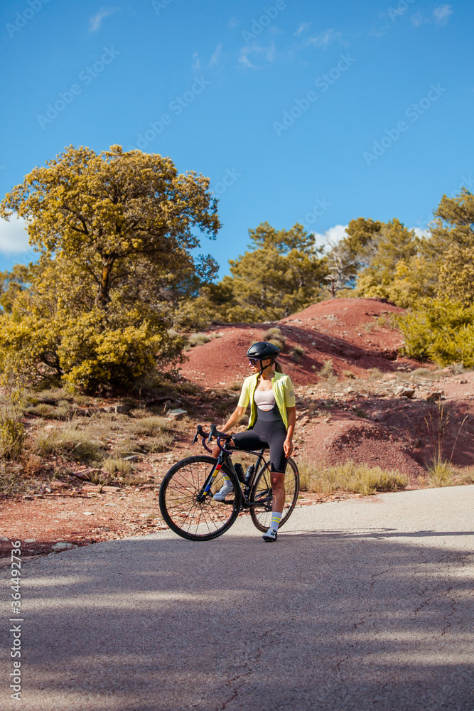 Young woman standing in the middle of the road with her road cycling bicycle