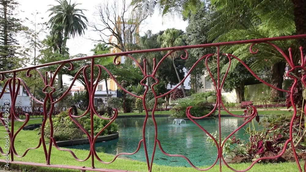 Decorative red fence in a formal garden overlooking a fountain with birds walking and flying past. Decorative red fence in a formal garden overlooking a fountain with birds walking and flying past.