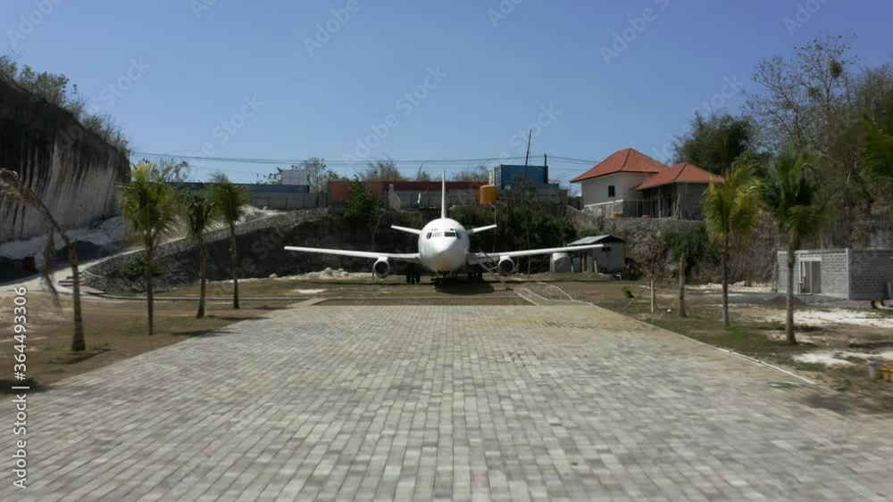 Approaching an abandoned airplane in the middle of a residential area on the island of Bali, Indonesia, aerial Approaching an abandoned airplane in the middle of a residential area on the island of Bali, Indonesia, aerial