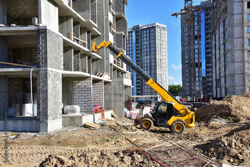 Telescopic handler work at the construction site. Construction machinery for loading. Tower crane during construct a multi-storey residential building. Wheel loader for lifting goods photo