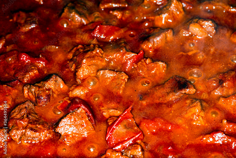 Traditional Hungarian goulash. Boiling beef stew with tomatoes and paprika, macro picture. Traditional Hungarian goulash. Boiling beef stew with tomatoes and paprika, macro picture.