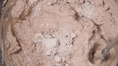 Slow motion pan shot of mixing concrete plaster with electric mixer. spatula and bucket with mortar on the construction site.