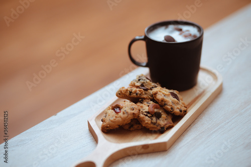 Cup of hot coffee and chocolate cookies for breakfast on wooden table