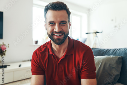 Handsome young man in casual clothing looking at camera and smiling while spendi Fototapet