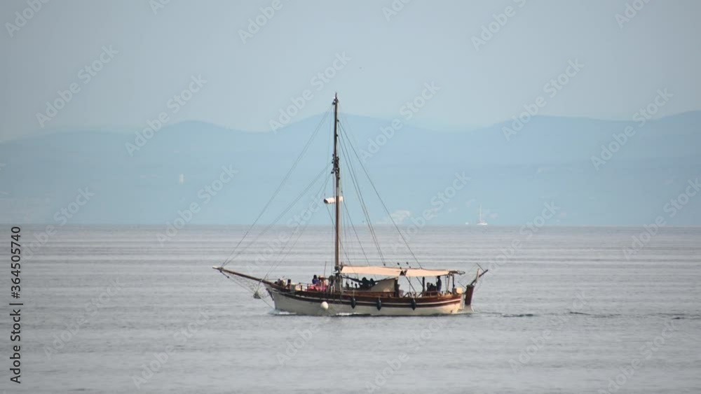 Wooden tourist boat and small private motor boat sailing on open sea in Gulf of Trieste, Slovenia. Mountains in the distance. Long shot, left pan Wooden tourist boat and small private motor boat sailing on open sea in Gulf of Trieste, Slovenia. Mountains in the distance. Long shot, left pan