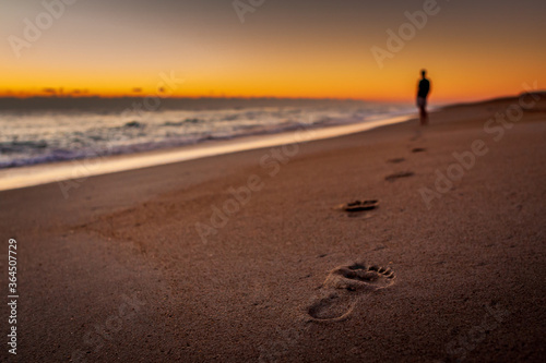 A person walking on the beach leaving footprints in the sand photo