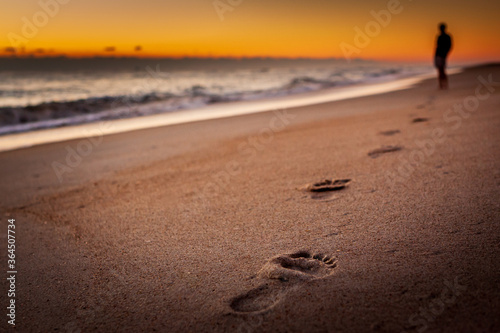A person walking on the beach leaving footprints in the sand photo