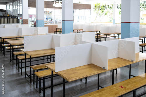 Corrugated plastic sheet partition on the tables in the cafeteria at school during its reopening plastic shield as a barrier to prevention of infection safety of students social distancing new normal