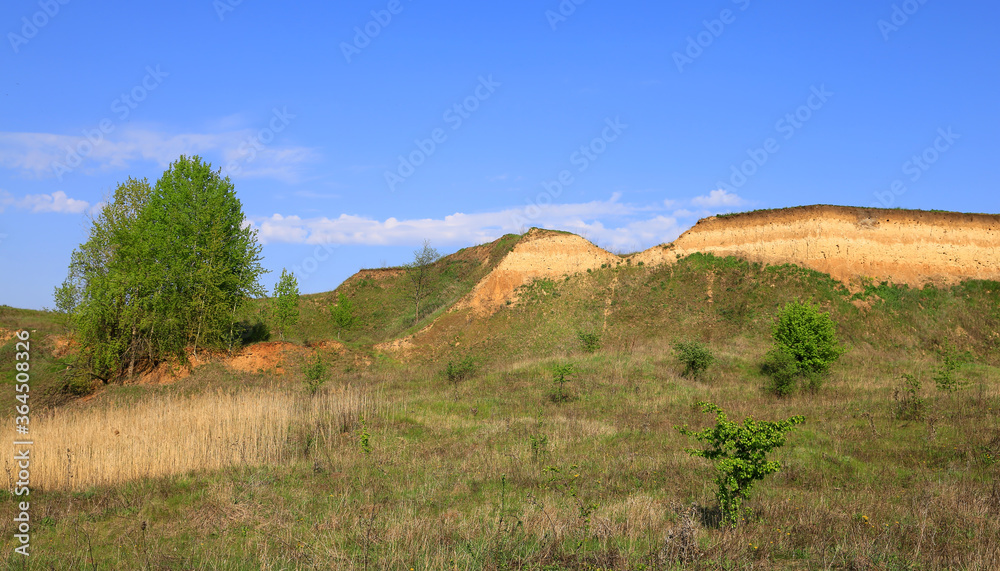 landscape with a cliff of clay over a green field