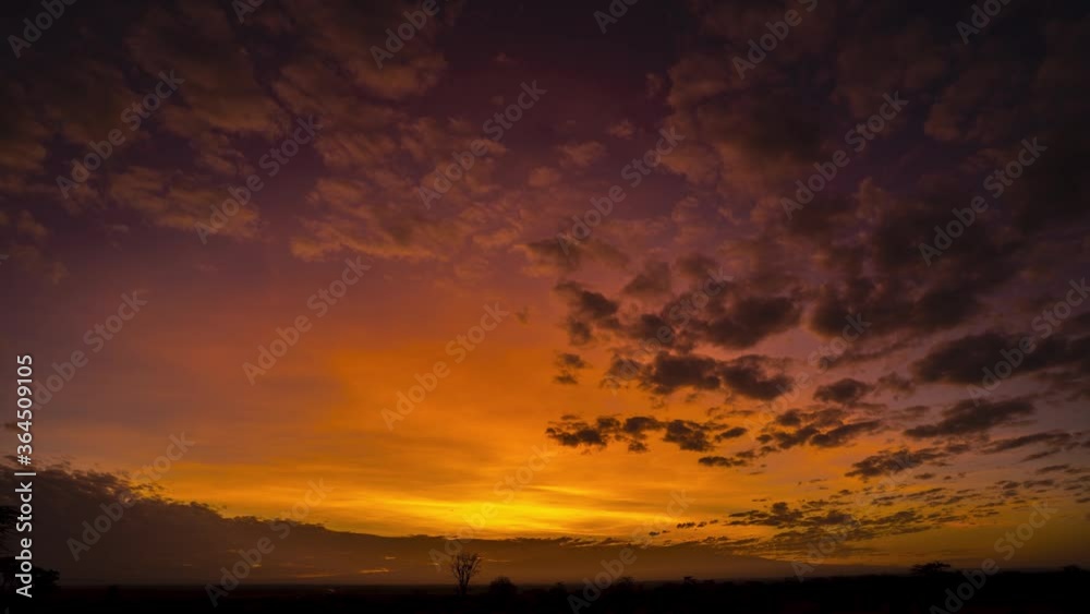 Stunning sunrise timelapse over African plains with mountains and red sky, clouds illuminated